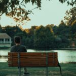 Person sitting alone in nature and reflecting on creativity